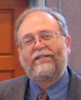 Lawrence Samuels headshot, wearing smile suit tie glasses (color photo)